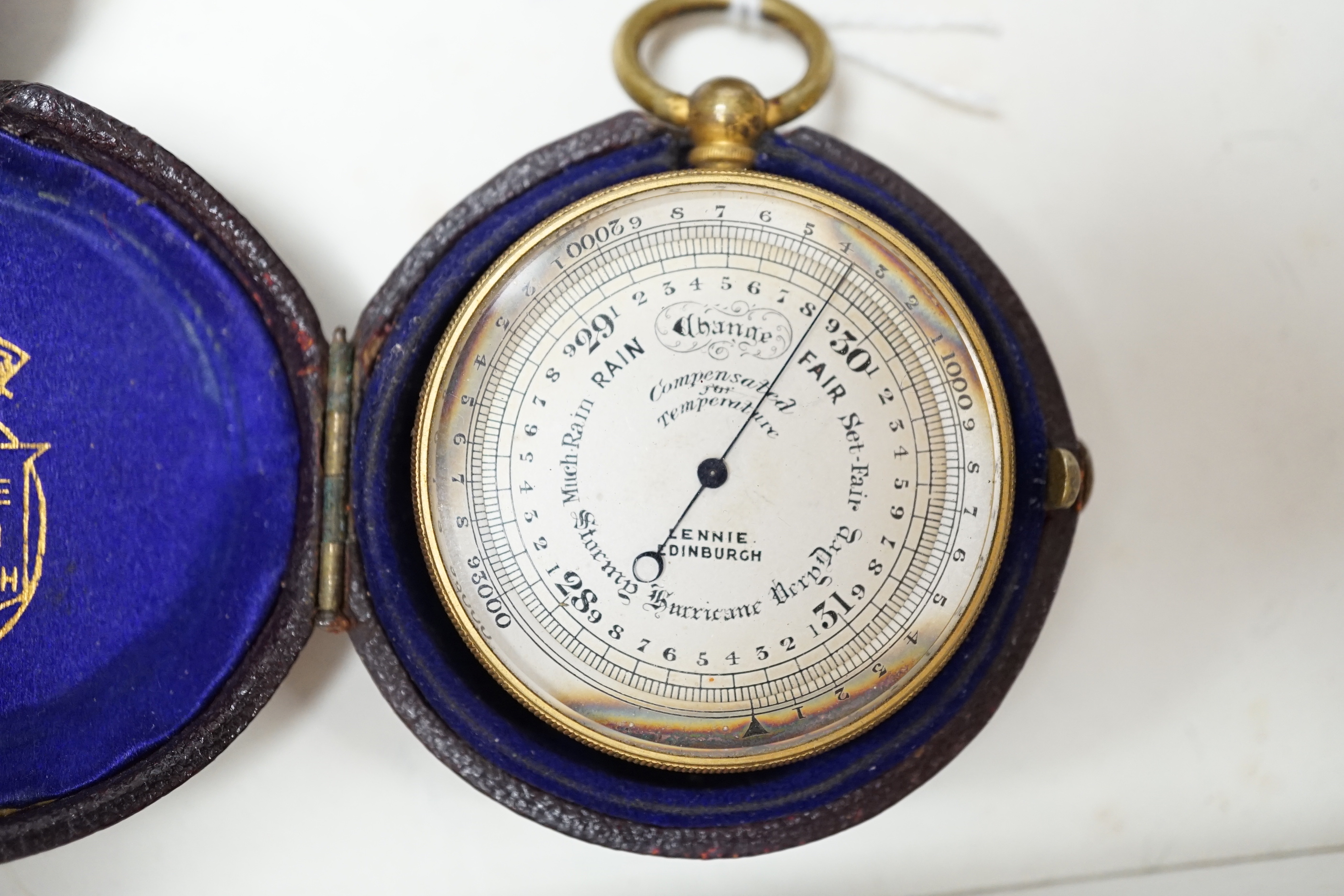 A Lennie brass pocket barometer, a carved coquilla nut, a silver plated napkin ring and two exhibition medallions